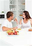 Cute woman giving bread to his husband during breakfast in the kitchen at home