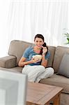 Woman laughing while watching a movie on television in the living room at home