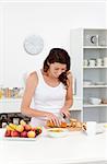 Joyful woman cutting bread for breakfast standing in the kitchen at home