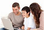 Cute family working on their laptop together sitting on the sofa at home