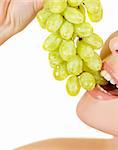 Closeup of woman mouth with green grape on a white