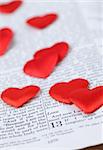 Bible open to 1st Corinthians 13, a passage about love, and little heart shaped confetti. Shallow dof