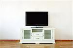 Large widescreen TV set on the white dresser in a bright room.