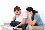 Worried couple looking at their bills on the sofa at home