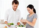 Happy woman serving salad to his boyfriend for the lunch in the kitchen