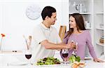 Attentive man serving salad to his girlfriend standing in the kitchen