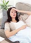 Sick woman lying on the sofa and touching her forehead to feel the temperature