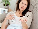 Close up of a woman taking her medicine on the sofa at home