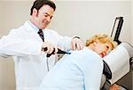 Friendly, smiling chiropractor adjusting a senior woman's back.