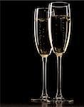Two full glasses of champagne over dark background