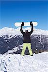 Man standing with snowboard over his head