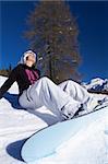 Cute Gril with snowboard is taking sunbath on snow