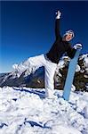 Girl holding snowboard on top of mountain, blue sky background