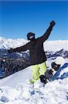 Snowboarder in black jacket posing in snowy mountains