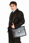 Serious young businessman holding briefcase on shoulder isolated on white
