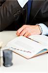 Business man sitting at office desk with diary.  Close-up on hands.