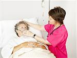 Hospital nurse helps a senior woman breath through an oxygen mask.