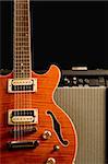 orange electric guitar with amplifier isolted on black