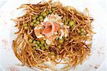 Closeup of salad with salmon fish at fried sliced potato with carrot and peas dressed by tomato sauce with cognac