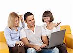 Three happy young adult people sitting with laptop computer on bright yellow sofa