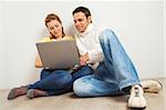 Young happy woman and man sitting together with laptop computer