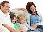 Parents and children watching television together on the sofa