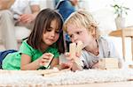 Little boy and girl playing with dominoes together in the living room