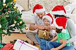 Family unwrapping gifts near the christmas tree