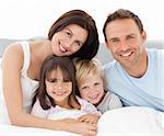 Portrait of a happy family sitting on the bed in the morning