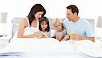 Lovely family having breakfast on the bed at home