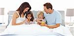Adorable children having breakfast on the bed with their parents at home