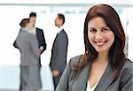 Happy businesswoman posing while her team discussing on the background