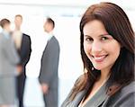 Charismatic businesswoman posing in front of her team while talking on the background