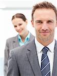 Confident businesswoman and businessman posing together in line at work