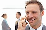 Handsome businessman on the phone while his partners standing on the background