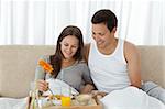 Young woman having breakfast on the bed with her boyfriend at home