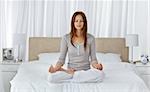 Young woman doing yoga exercises on the bed at home