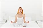 Woman practicing yoga on her bed at home