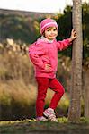 A picture of a young cute girl posing by the tree in the park