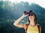 young caucasian female hiker watching through binoculars. Horizontal shape, front view, head and shoulders, copy space