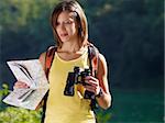 young caucasian female hiker reading map and holding binoculars. Horizontal shape, waist up, copy space