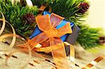 Christmas blue gift box with orange bow against fir branch on golden background