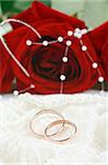 Wedding rings on lace against red rose