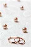 Wedding rings on lace light background with pearls