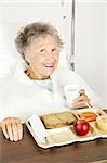 Senior woman in the hospital, eating her lunch from a tray.