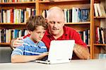 Teacher helping a student use a netbook computer in the school library.