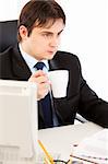 Thoughtful business man  sitting at office desk  and holding cup of tea in hand