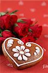 Gingerbread heart and red roses on red background. Shallow dof