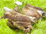 Well-done pork edges are located on leaves of salad and decorated by parsley greens