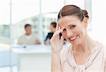 Smiling businesswoman looking at the camera while her coworkers are talking in the office